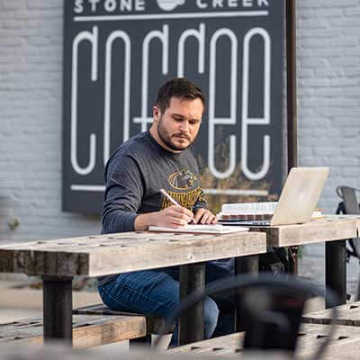 UWM Online student working on school work at a coffee shop.