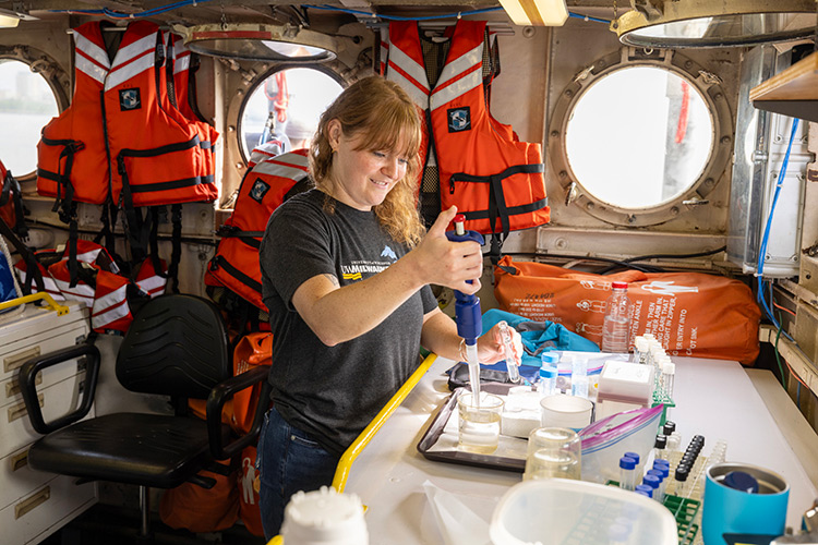 A student performing lab tests of water in the cabin of the Neeskay.