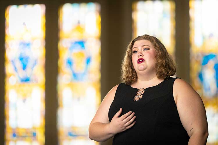 UWM music student Scotlyn singing and standing in front of stained glass